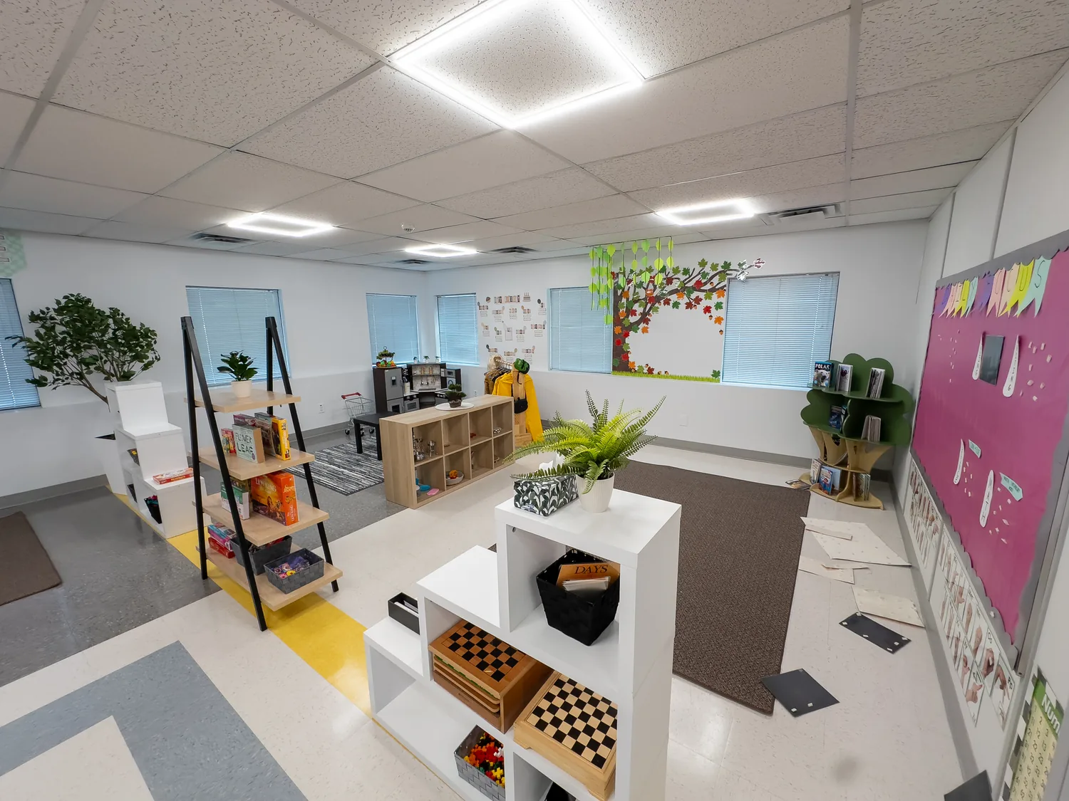 An open playroom with a tree mural along the windows