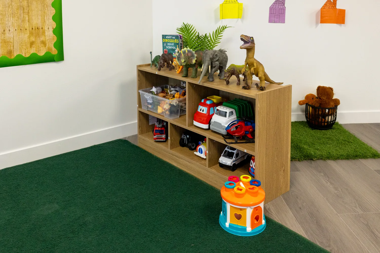 A shelf of dinosaurs above baskets of vehicles