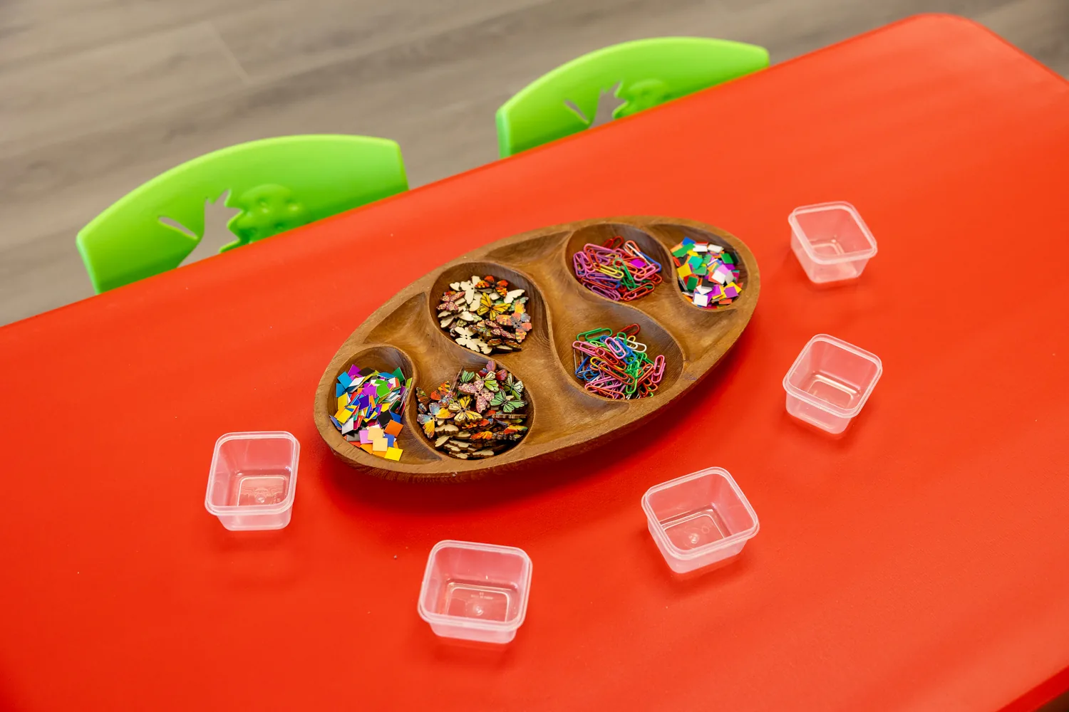 Loose parts and beads sorted into a wooden tray