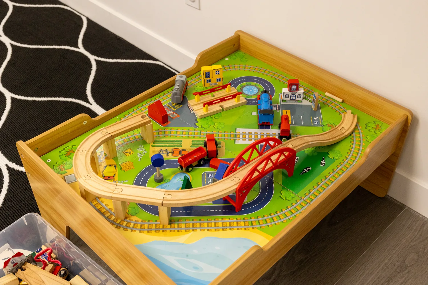 A wooden train table with track and engines